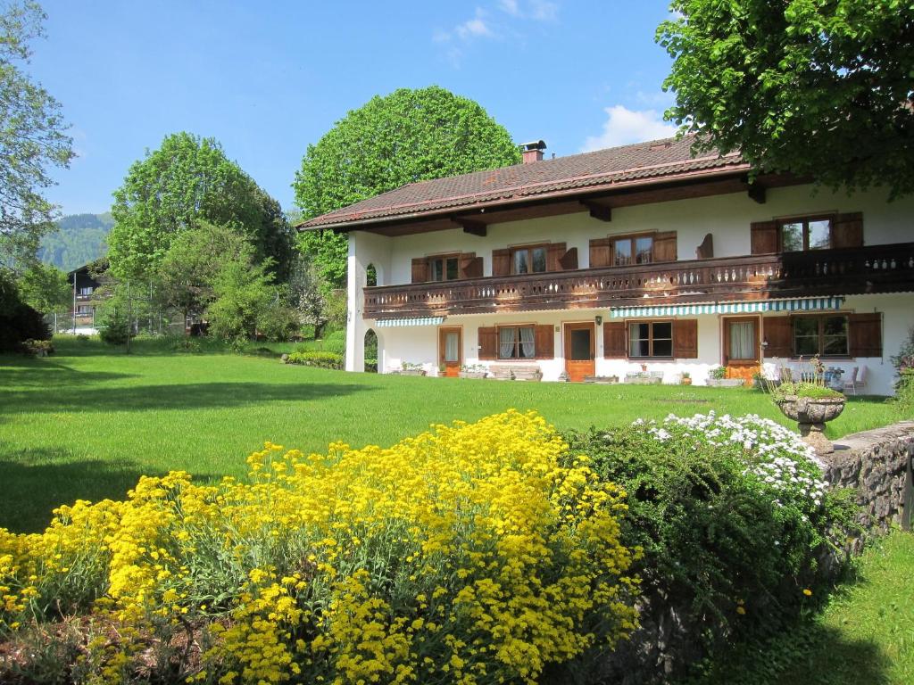 a large house with yellow flowers in the yard at Ferienwohnungen Elisabeth am See in Rottach-Egern