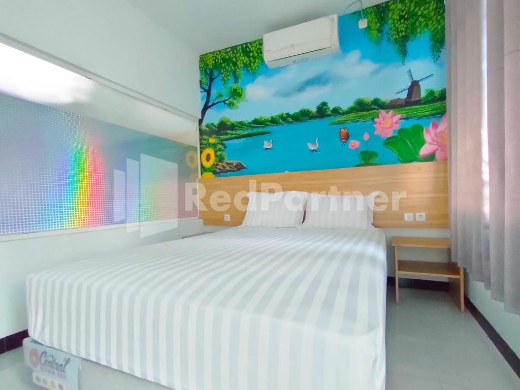 1 dormitorio con 1 cama blanca y un mural de arco iris en la pared en Joy Homestay Near UMJ Jember Mitra RedDoorz en Jember