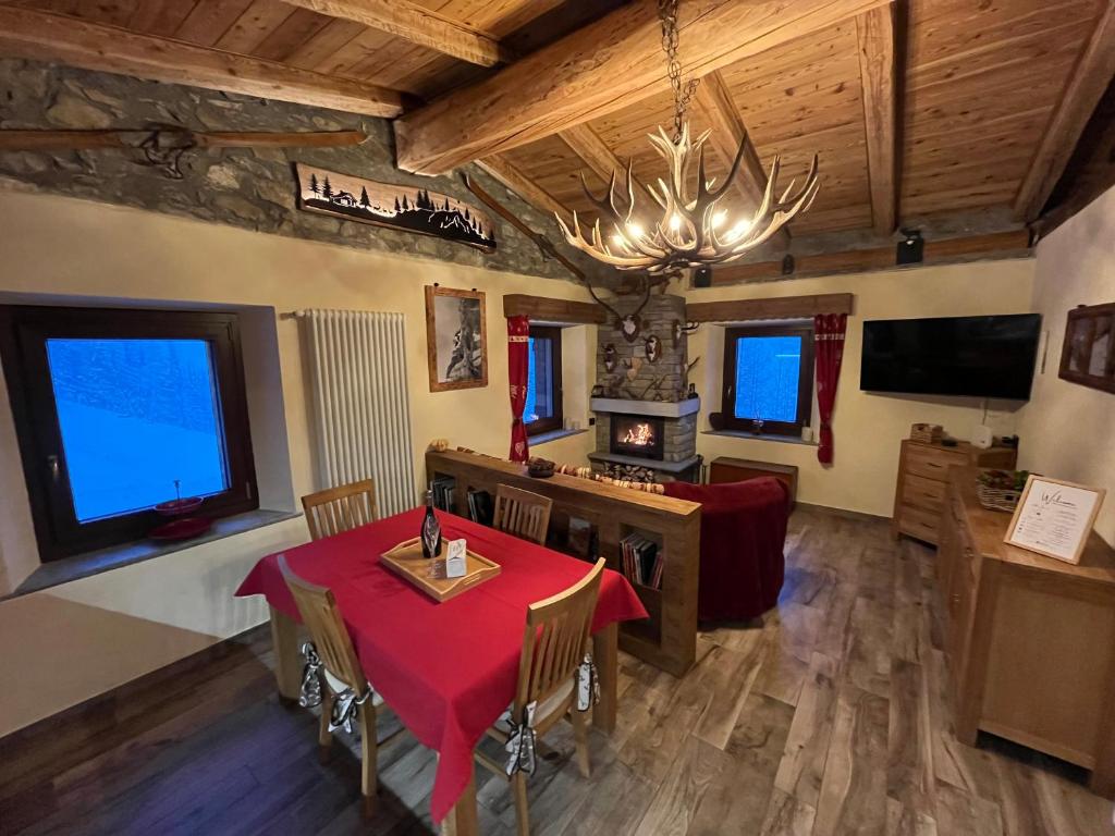 un comedor con una mesa y sillas rojas y una lámpara de araña en Chalet Chez Louis vista Catena Monte Bianco sulle piste da sci en Courmayeur