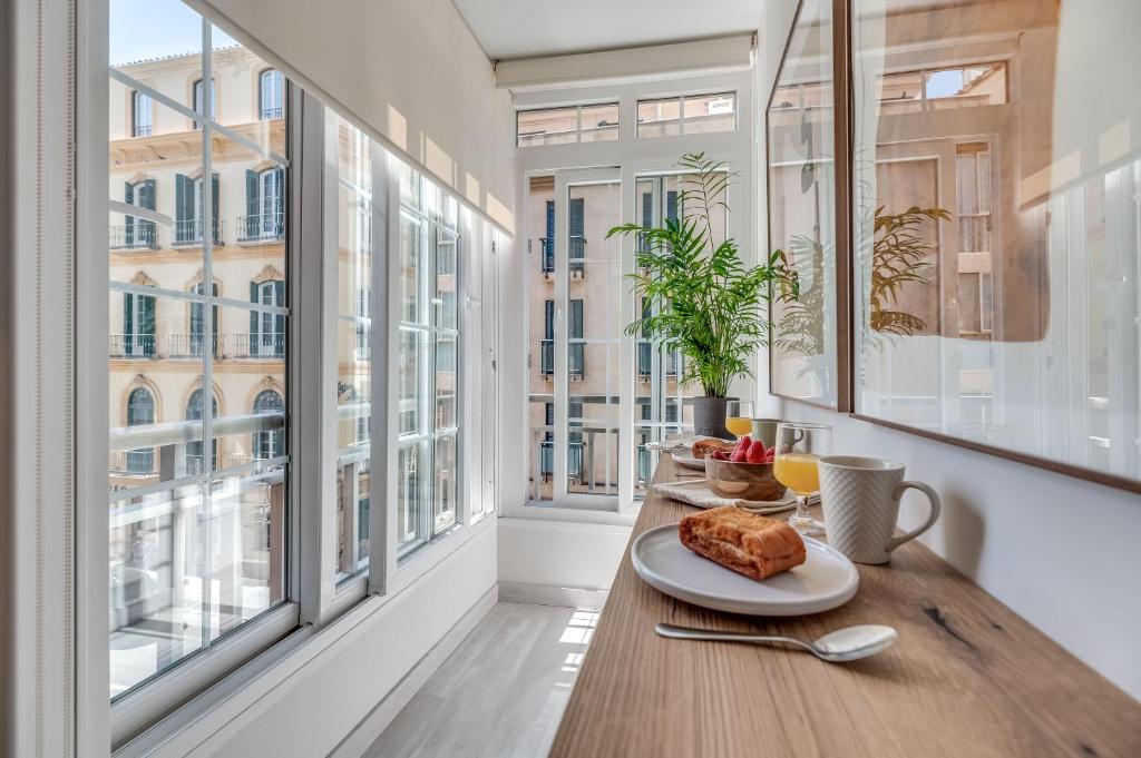 einen Frühstückstisch in einem Zimmer mit großen Fenstern in der Unterkunft Victoria 16 Premium by Nagoa Homes in Málaga