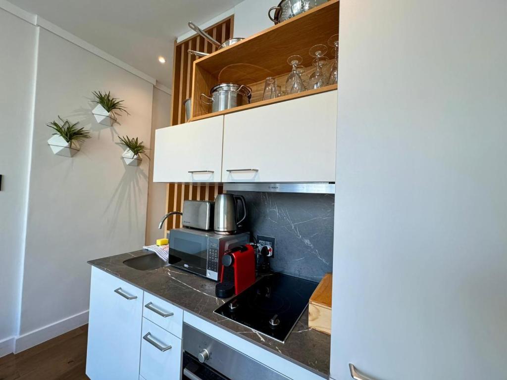 a kitchen with white cabinets and a microwave at Bree Street Apartment - Explore, Eat, Experience Cape Town in Cape Town