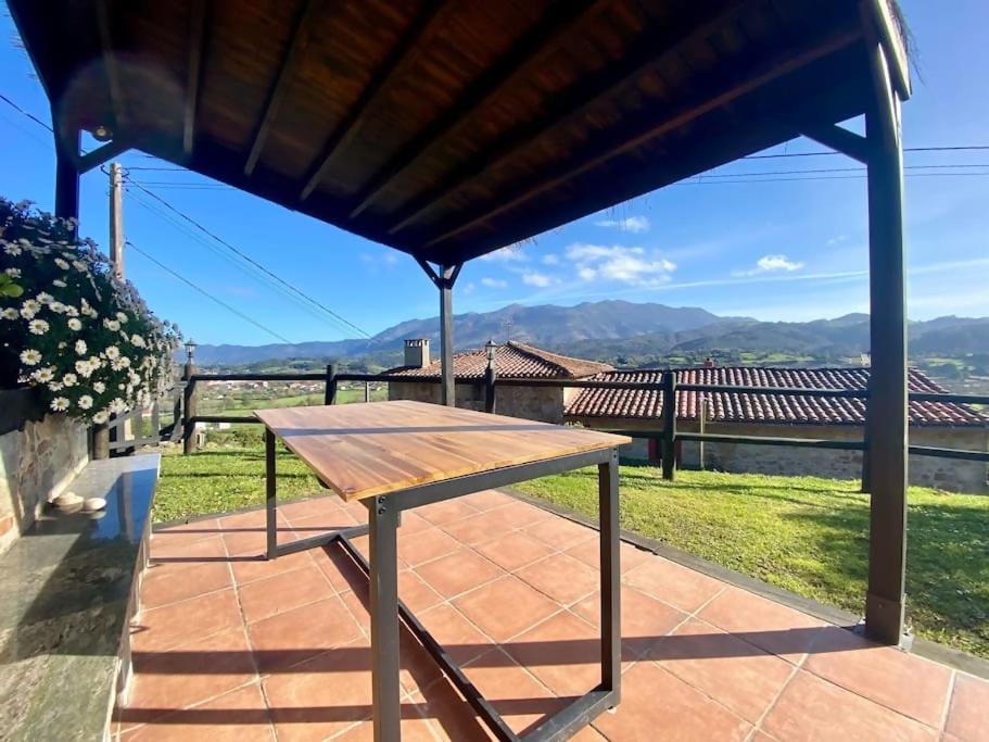 a wooden table sitting under a pavilion on a patio at Casa en aldea frente a la Sierra de el Sueve in Colunga