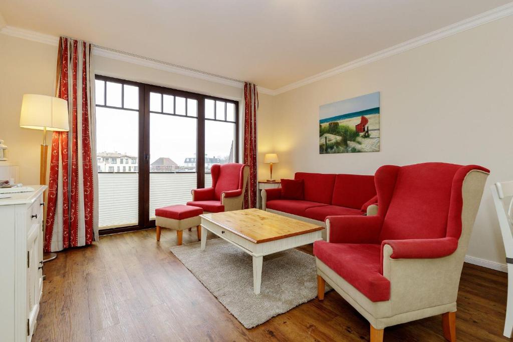 a living room with a red couch and two chairs at Urlaubstraeume-am-Meer-Wohnung-5-8-645 in Kühlungsborn