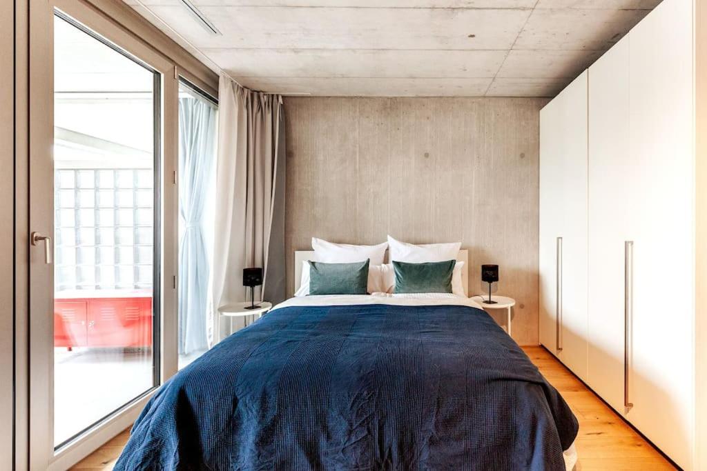 a bedroom with a large bed and a large window at Designer-Maisonette im Industrie Chic 3,5 Zimmer in Zurich