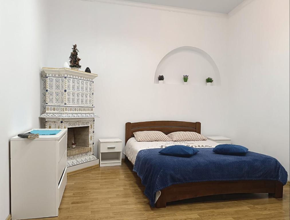 ein weißes Schlafzimmer mit einem Bett und einem Kamin in der Unterkunft Apartments Anna in Lwiw