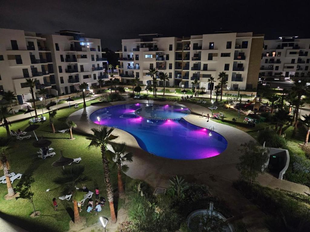 einem großen Pool mit lilafarbenen Lichtern vor einem Gebäude in der Unterkunft MARTIL COSTA MAR Appartement de Luxe in Martil