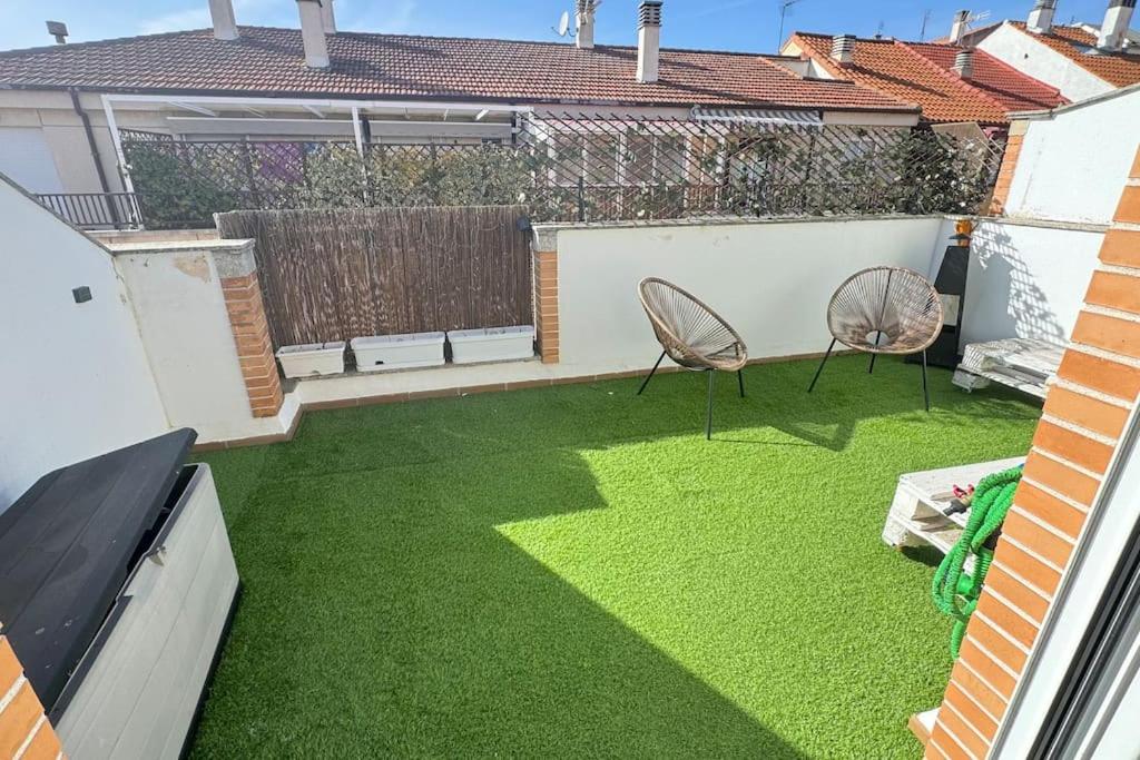 un pequeño patio trasero con césped verde y 2 sillas en Precioso ático con garaje gratis en Salamanca
