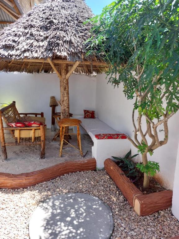 pokój z łóżkiem, stołem i drzewem w obiekcie Nungwi beach house II w mieście Nungwi