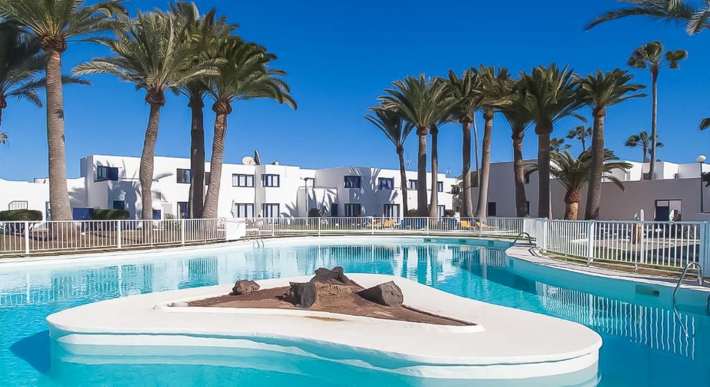 a swimming pool with palm trees in the background at Los Barqueros 25 by Best Holidays Fuerteventura in Corralejo