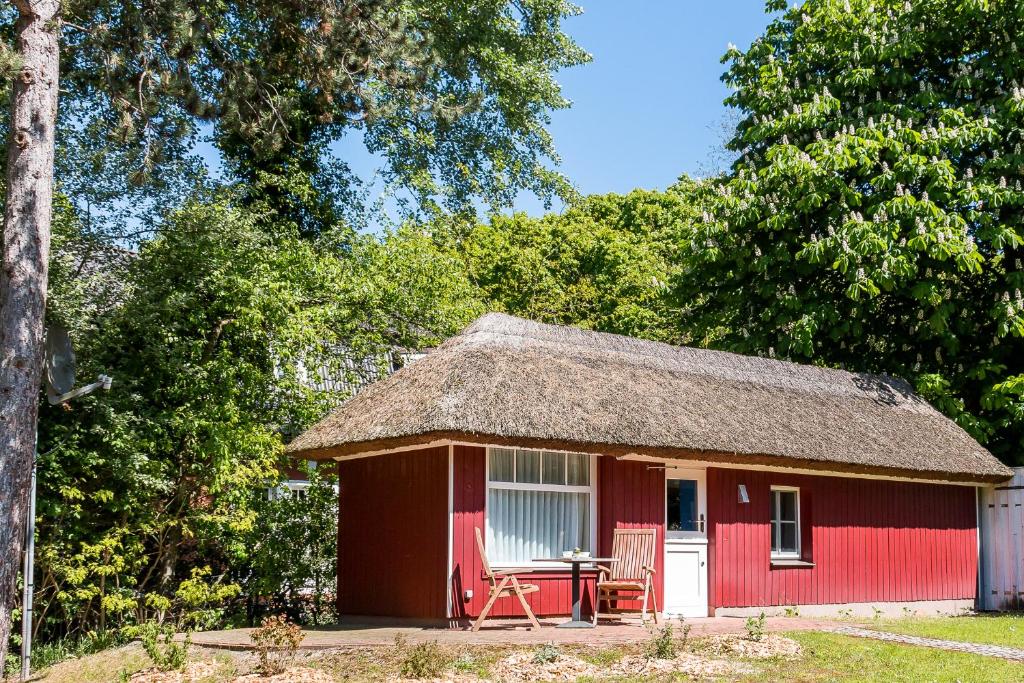 a red and white shed with a table and chairs at Dat Lütthus in Ahrenshoop