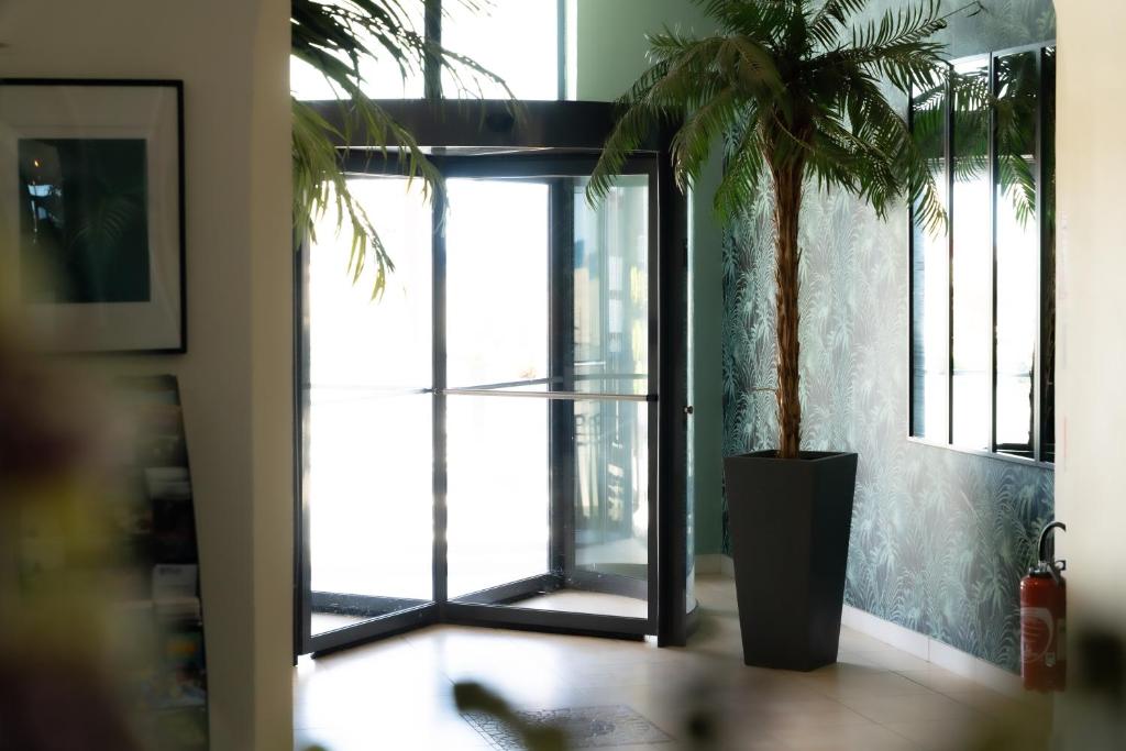 a potted palm tree in a room with a glass door at Hôtel Mar I Cel &amp; Spa in Canet-en-Roussillon