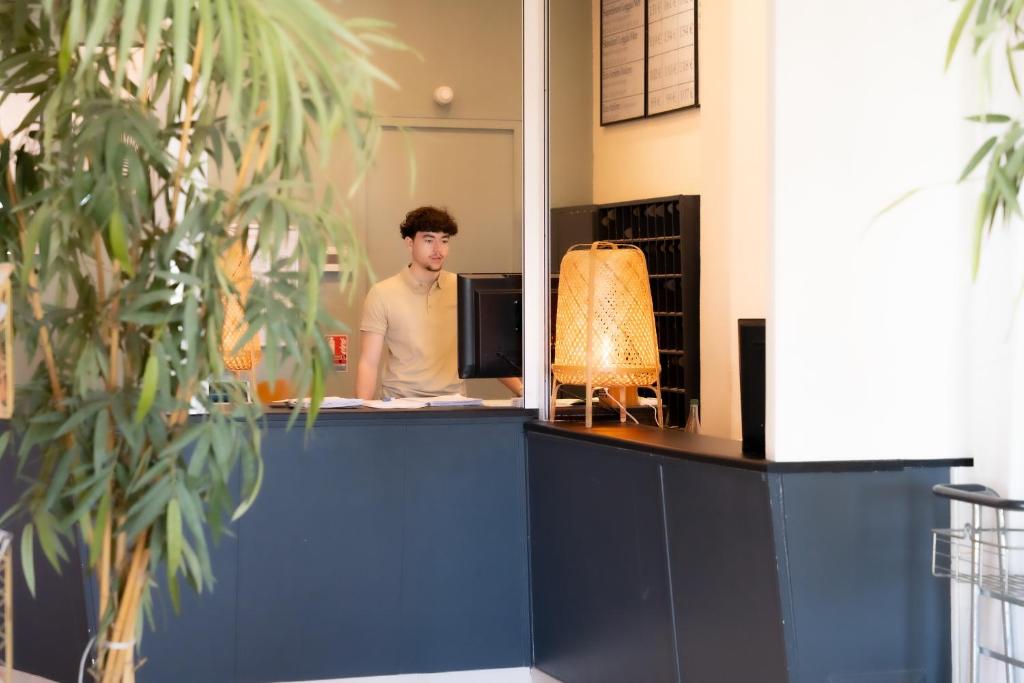 a man standing at a counter in an office at Hôtel Mar I Cel &amp; Spa in Canet-en-Roussillon