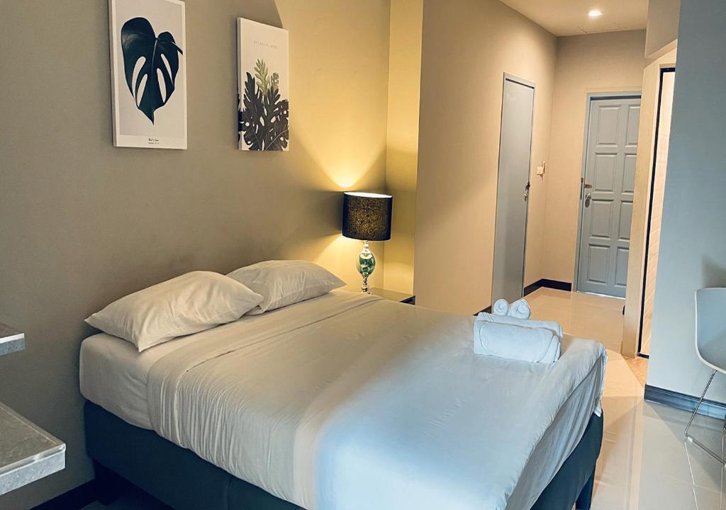 1 dormitorio con 1 cama grande con sábanas blancas en The Green Plaza Hotel, en Bangrak Beach