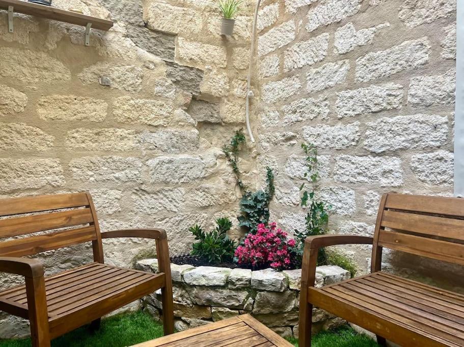 deux bancs en bois assis devant un mur en pierre dans l'établissement Le Laurier-rose, à Montpellier