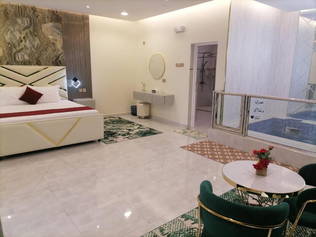 尼茲瓦的住宿－MY HOTEL AL YAQOT 3 POOLS VILLA - NIZWA，酒店客房带一张床、一张桌子和椅子