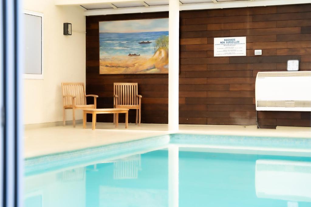 a swimming pool with two chairs and a painting on the wall at Hôtel Mar I Cel &amp; Spa in Canet-en-Roussillon