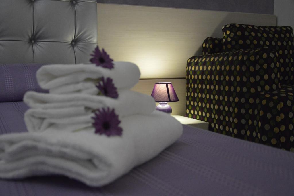 イスピカにあるIl Gheppioの白いタオルと紫色の花を添えたベッド