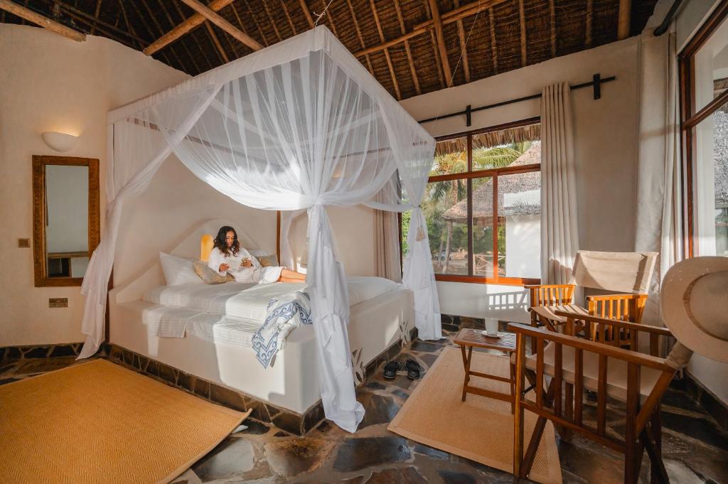 a woman sitting on a bed in a bedroom at Mwazaro Beach Lodge in Shimoni