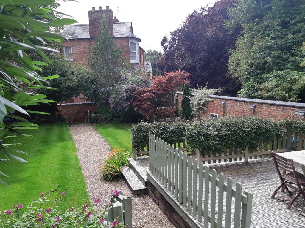 a garden with a wooden bench in front of a house at Beautiful Georgian cottage within a private walled garden in Oakham
