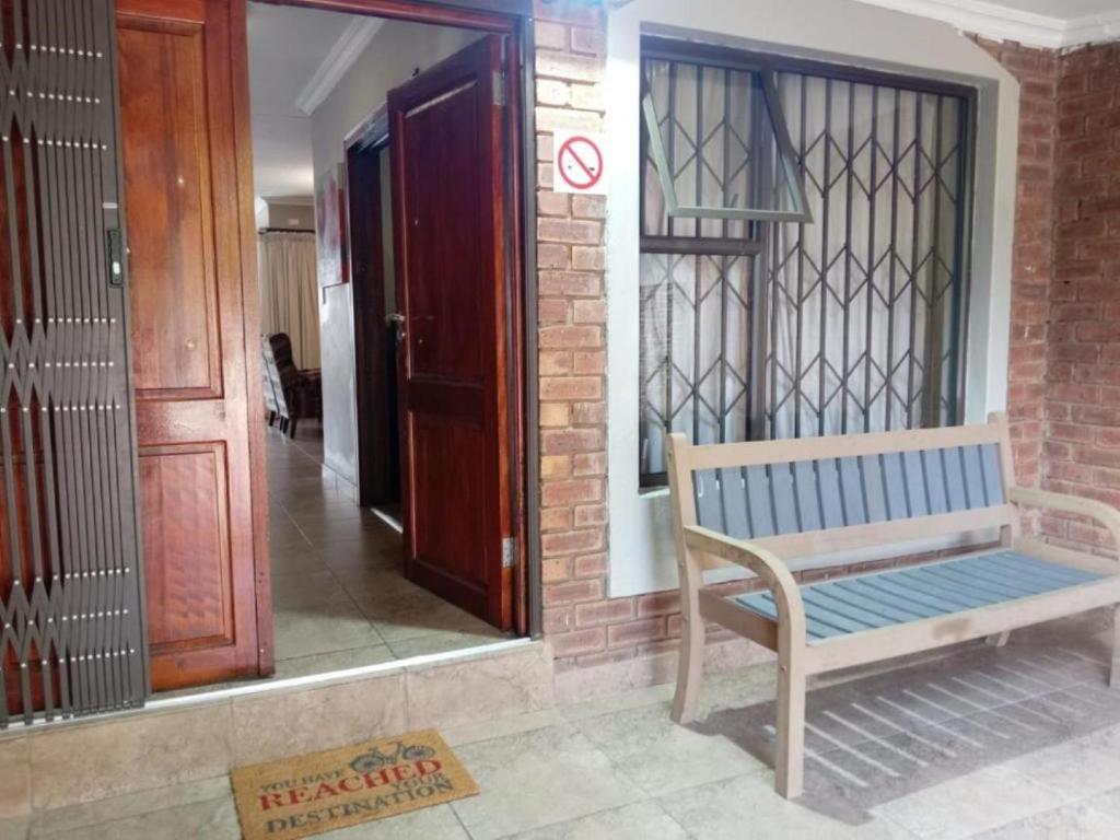 a wooden bench sitting outside of a building with a door at KWR B&B in Witbank