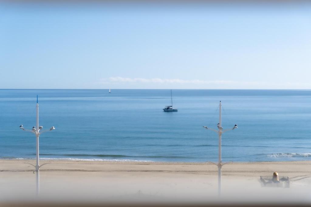 a view of the ocean with a boat in the water at Hôtel Mar I Cel &amp; Spa in Canet-en-Roussillon