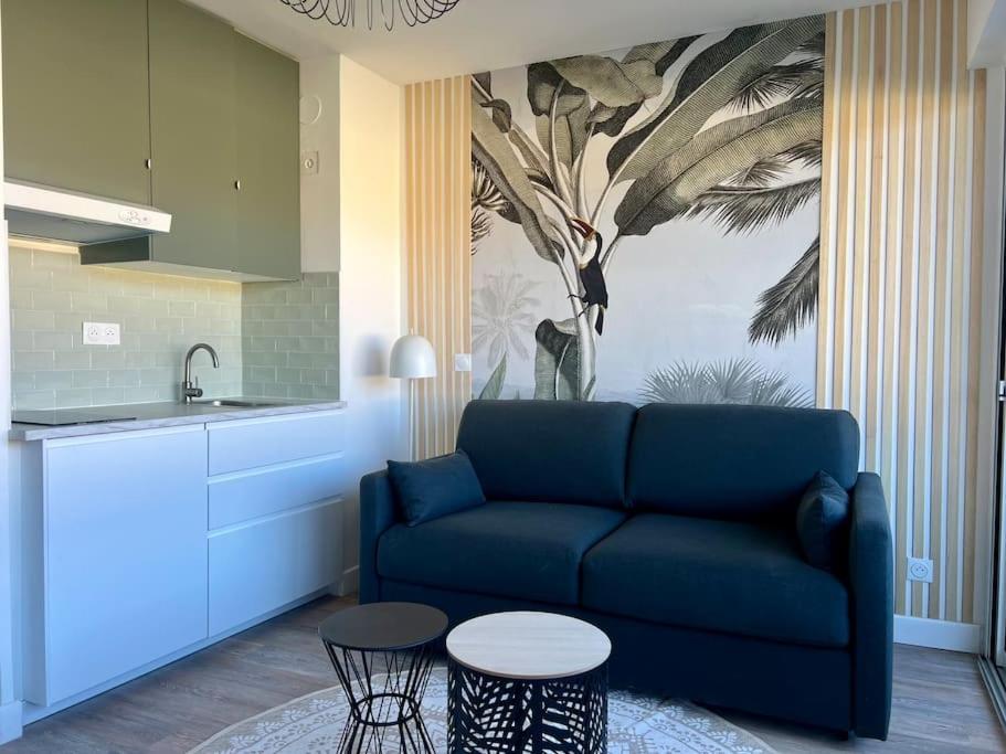 un salon avec un canapé bleu et deux tables dans l'établissement Le Beauséjour, à Montpellier