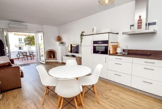 a white kitchen with a table and white chairs at CASITA BONITA NERJA in Nerja