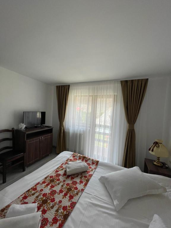Un dormitorio con una gran cama blanca con una manta de flores rojas en Green Mountain Resort, en Scrind-Frăsinet