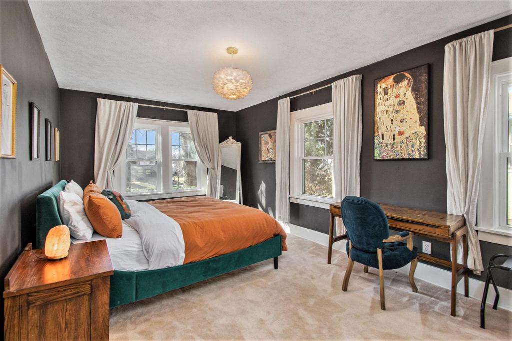 a bedroom with a bed and a desk and windows at Large Midtown Home With King Beds, Bunk Room, and Arcade in Omaha