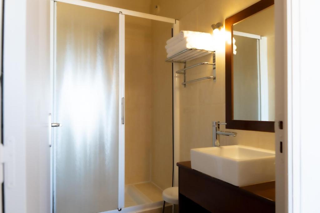 a bathroom with a shower and a sink and a mirror at Hôtel Mar I Cel &amp; Spa in Canet-en-Roussillon