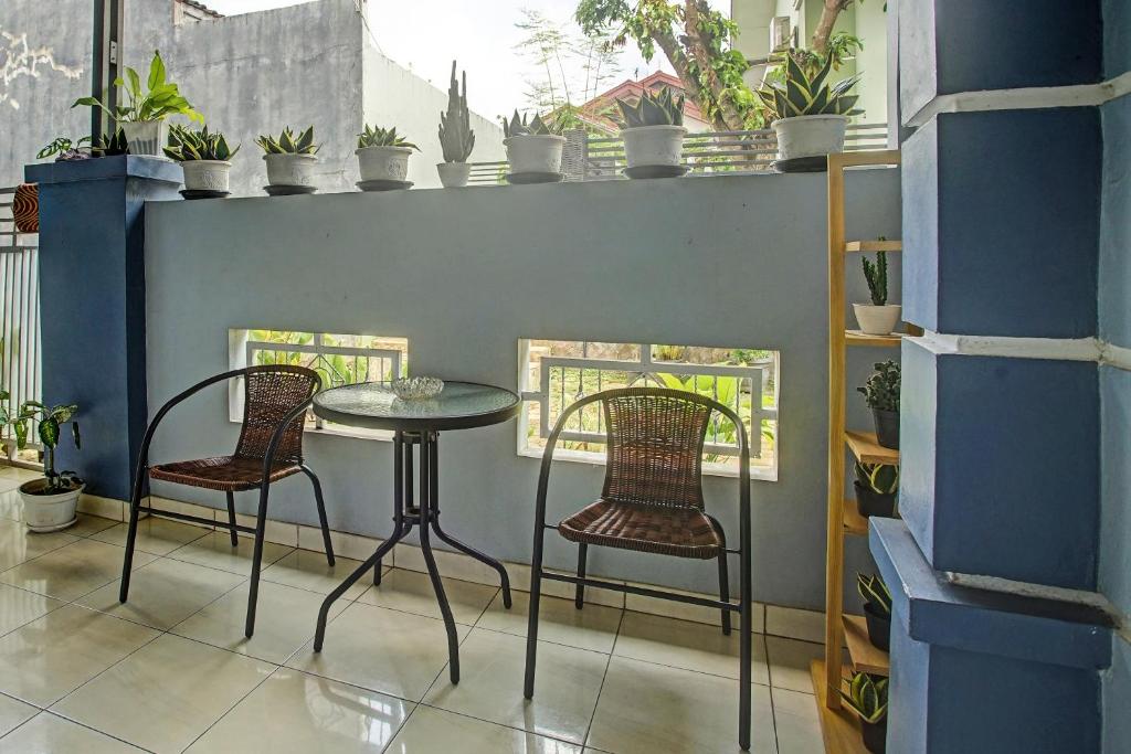 een tafel en twee stoelen in een kamer met planten bij OYO 3994 Wisma Amalia in Bandar Lampung