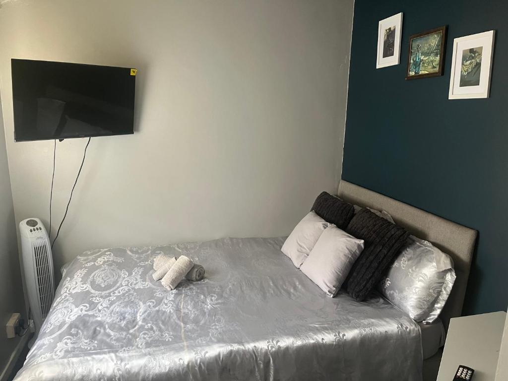 Schlafzimmer mit einem Bett und einem Flachbild-TV in der Unterkunft Queenomega’s home stay in London