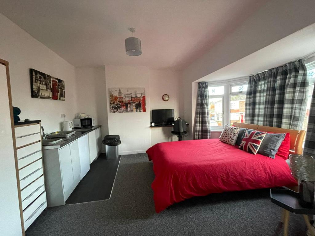 a bedroom with a red bed and a kitchen at Fionn House Darlington in Darlington