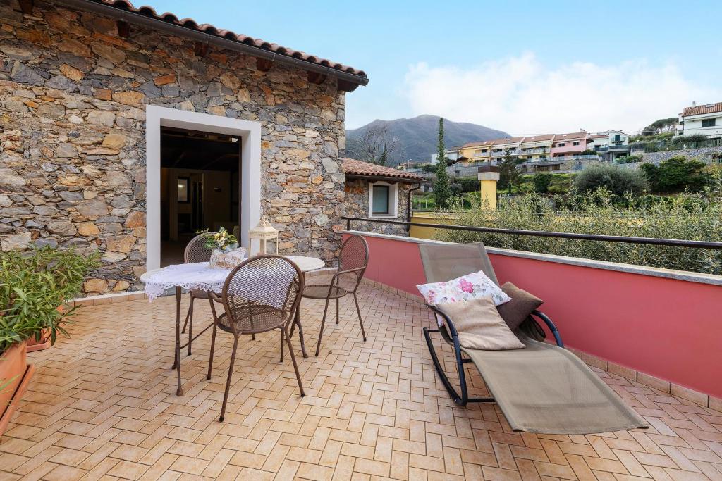 eine Terrasse mit einem Tisch und Stühlen auf dem Balkon in der Unterkunft Pesco Agriturismo La Ferla in Toirano