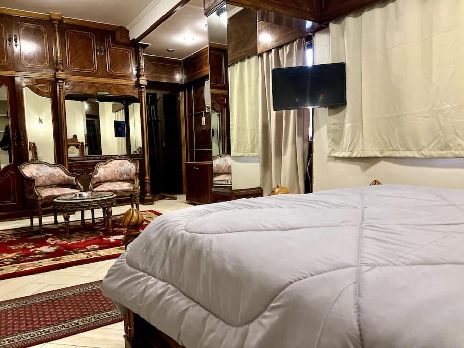 a bedroom with a large bed and a living room at 4-Brs Historical Apt in Maadi 5-Min to Nile in Cairo