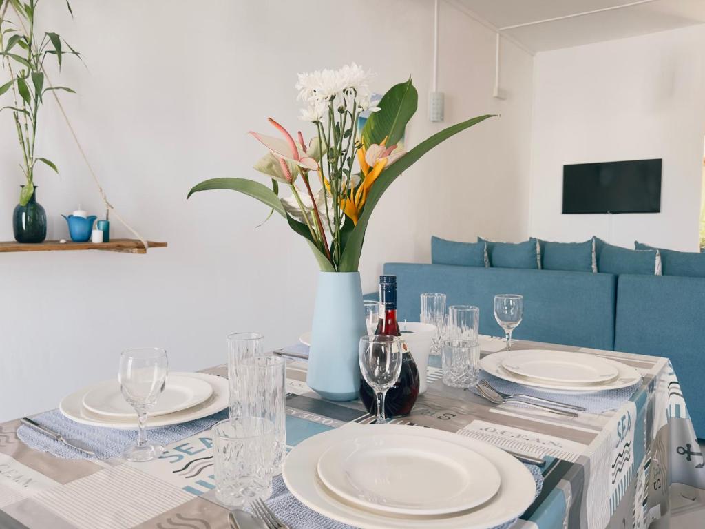 a table with plates and glasses and a vase with flowers at Residence Le Point Choisy in Pointe aux Cannoniers