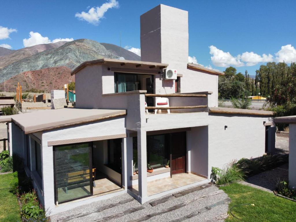 a white house with windows and mountains in the background at Moller Masi - Ayllu Huasi in Purmamarca
