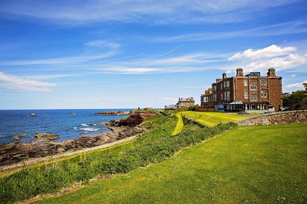 a large building on a hill next to the ocean at Bayswell Park Hotel in Dunbar