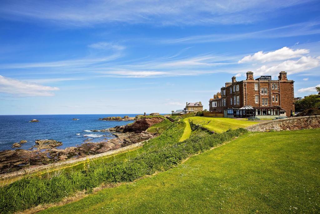 ein großes Gebäude auf einem Hügel neben dem Meer in der Unterkunft Bayswell Park Hotel in Dunbar