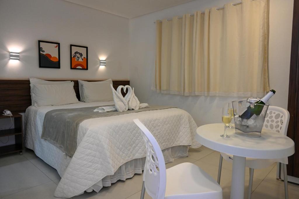 Un dormitorio con una cama y una mesa con una botella de vino en Pousada Galemares, en Maragogi