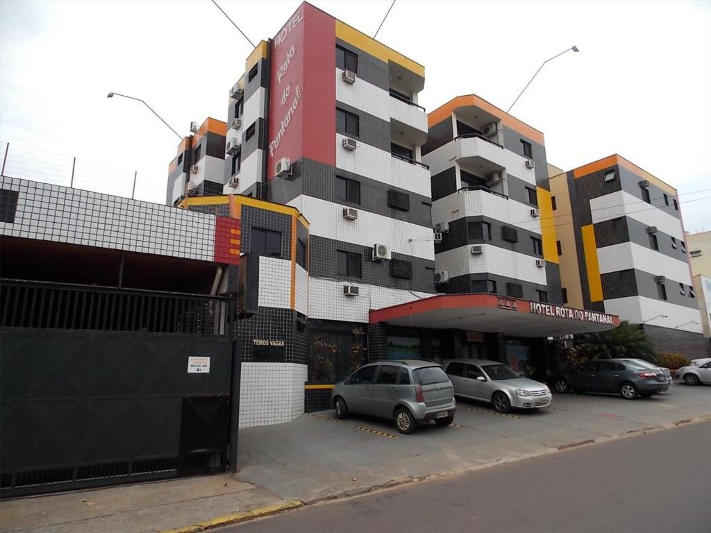 un estacionamiento con autos estacionados frente a un edificio en Hotel Rota do Pantanal, en Presidente Prudente