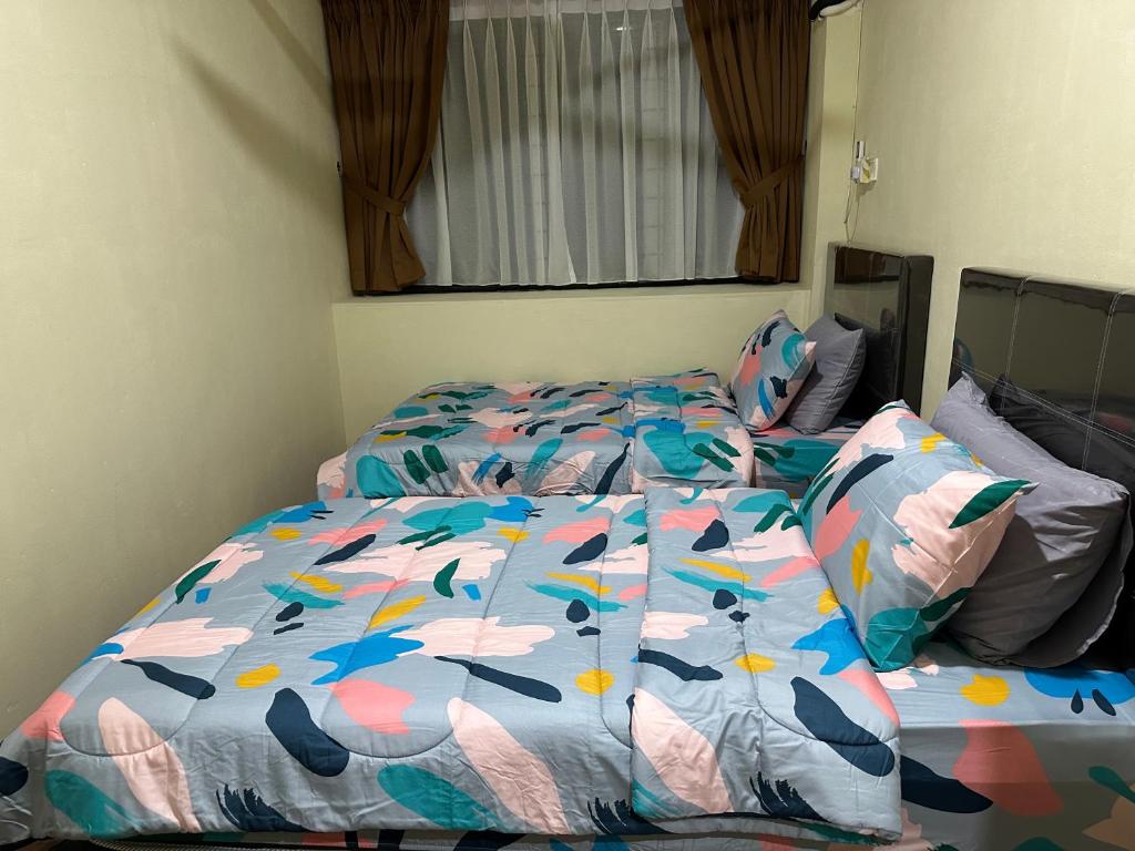 a bed with a comforter with birds on it at Belian Homestay Sibujaya in Sibu