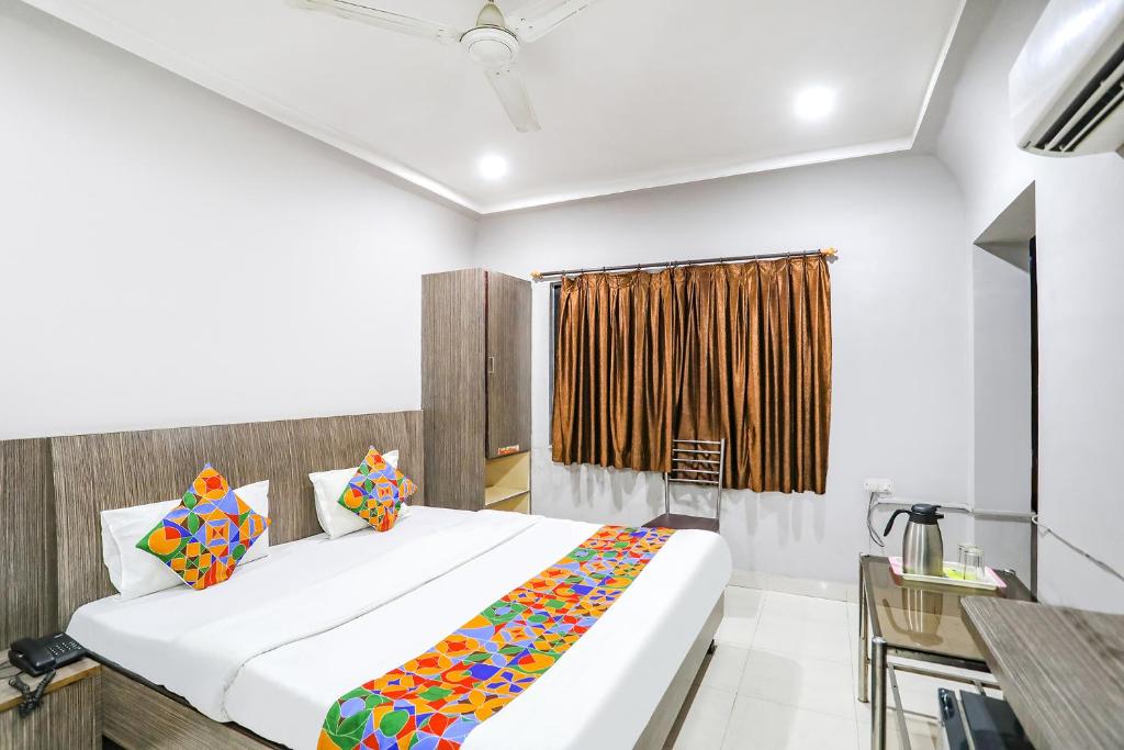 1 dormitorio con cama y escritorio en FabHotel Sun Om, en Raipur
