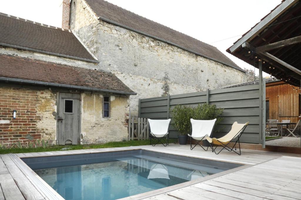 a backyard with a swimming pool and two chairs and a building at Maison de Campagne by La Boîte En Plus in Senlis