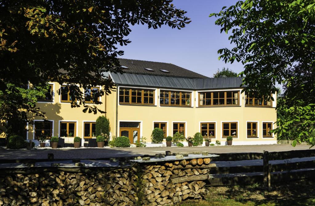 a large white house with a stone wall at Landhotel Hallnberg in Walpertskirchen
