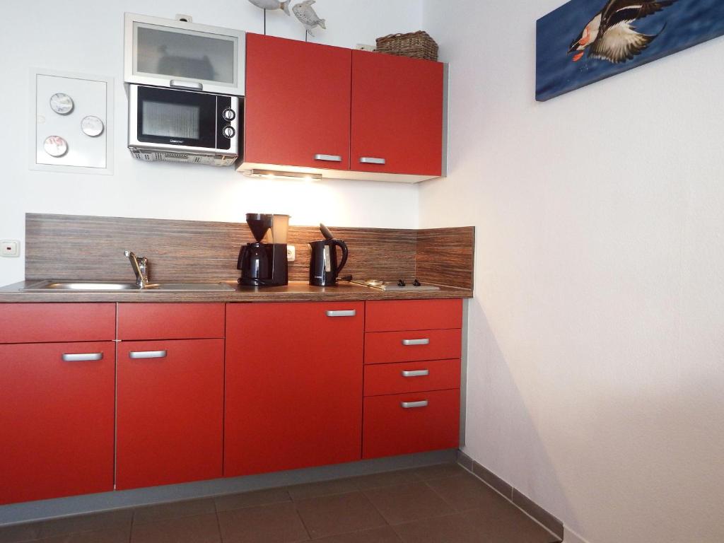 - une cuisine équipée de placards rouges et d'un four micro-ondes dans l'établissement Yachthafenresidenz-Wohnung-8106-9412, à Kühlungsborn