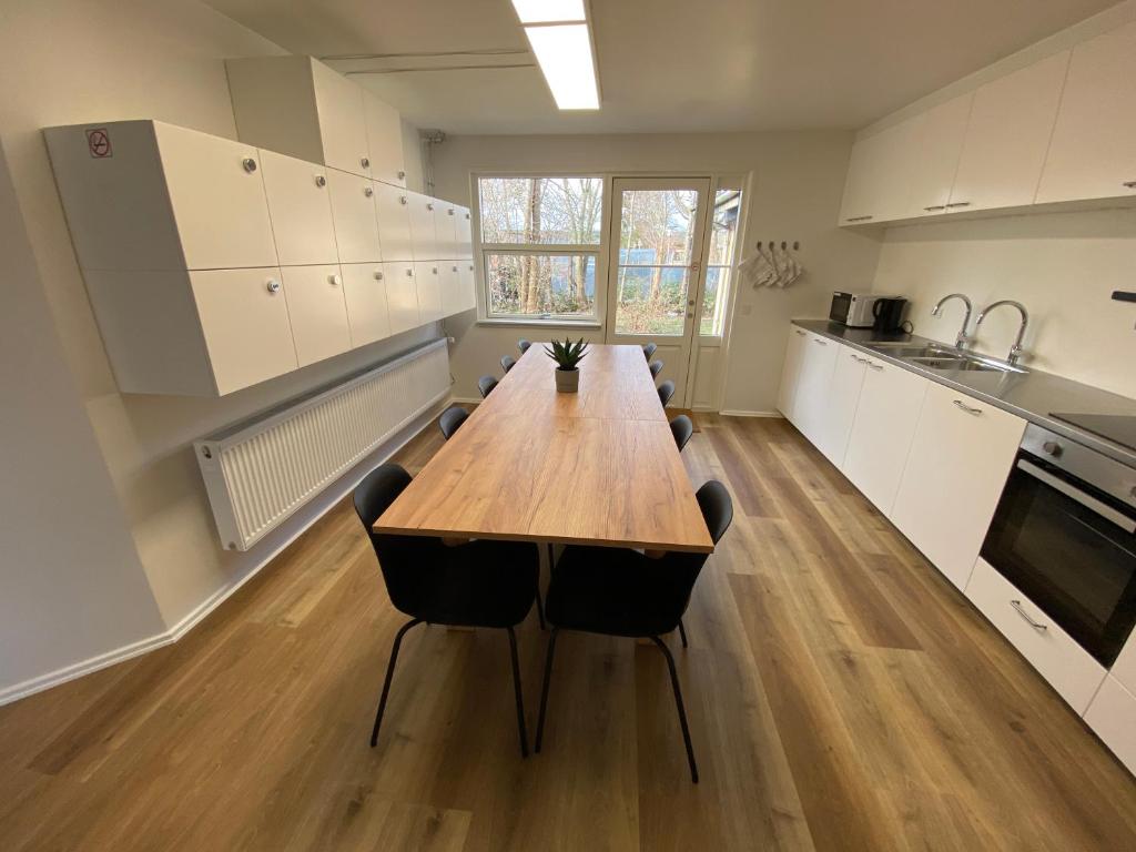 uma grande cozinha com uma mesa de madeira e cadeiras em Q Work - Hostel em Koege