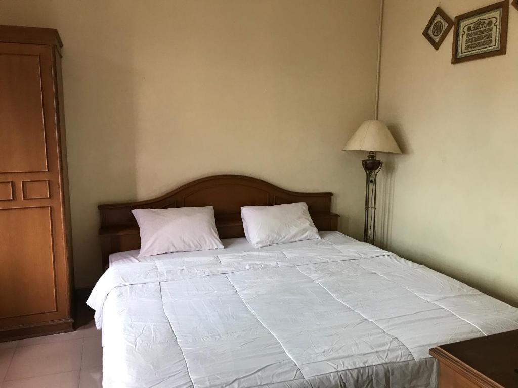 um quarto com uma cama grande e 2 almofadas brancas em Wisma Atma Bhakti RedPartner near Solo Square em Lawean