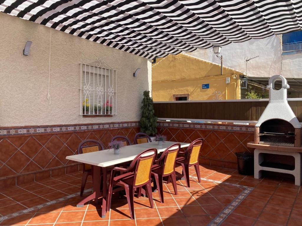 een patio met een tafel en stoelen en een grill bij Casa encantadora y confortable en Málaga. in Málaga