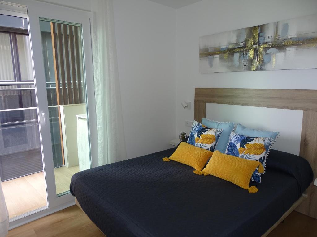 una camera da letto con letto con lenzuola blu e cuscini gialli di Andmar Beach Apartamento a Peñíscola